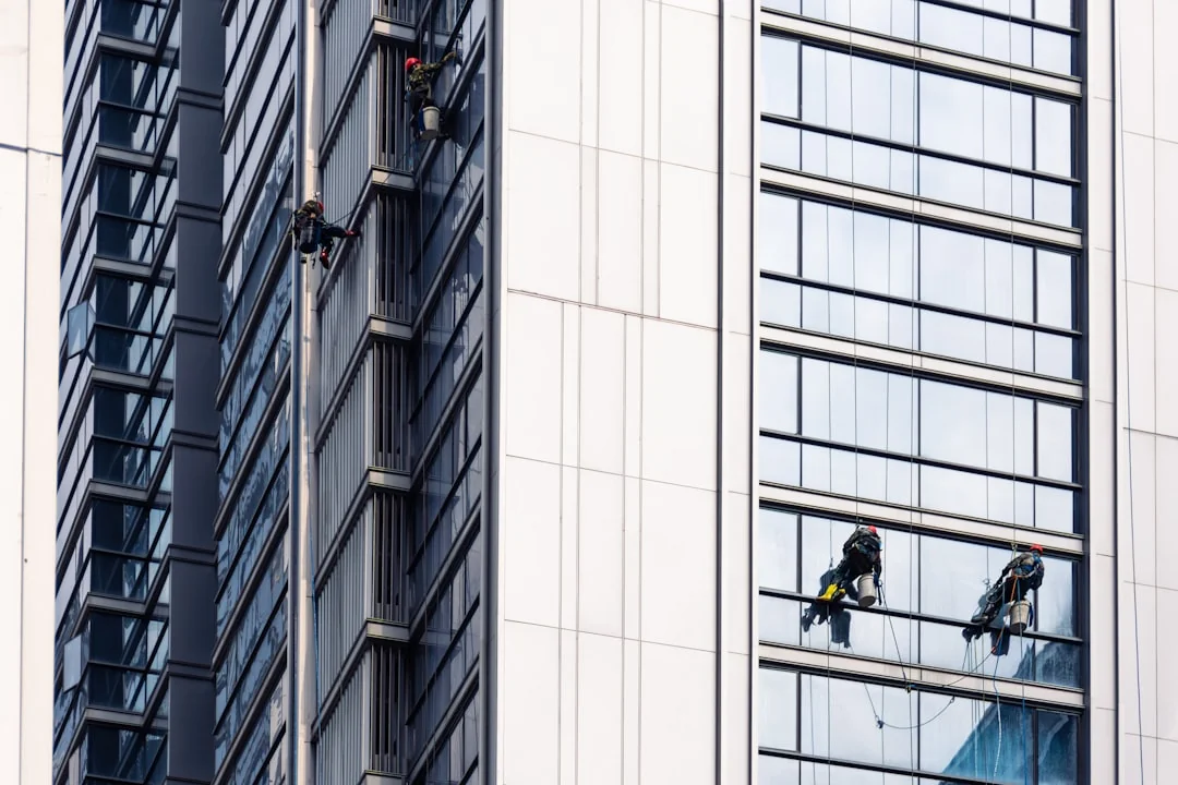 A man cleaning skyscraper windows with a harness, showcasing urban high-rise work.